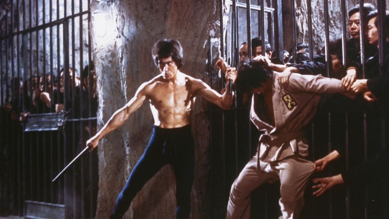 Bruce Lee fighting a man with a crowd